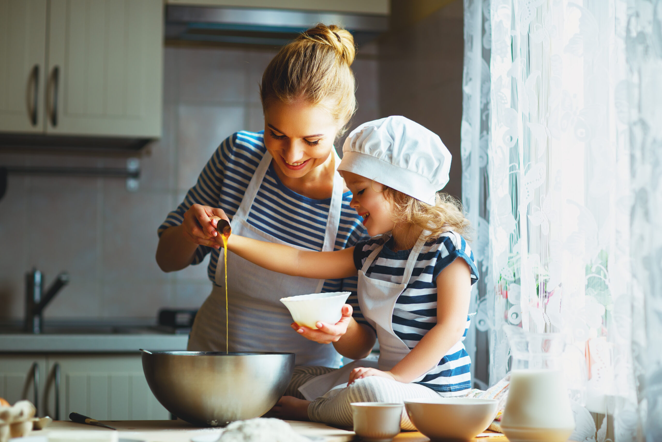 Single carer and young girl baking together in kitchen