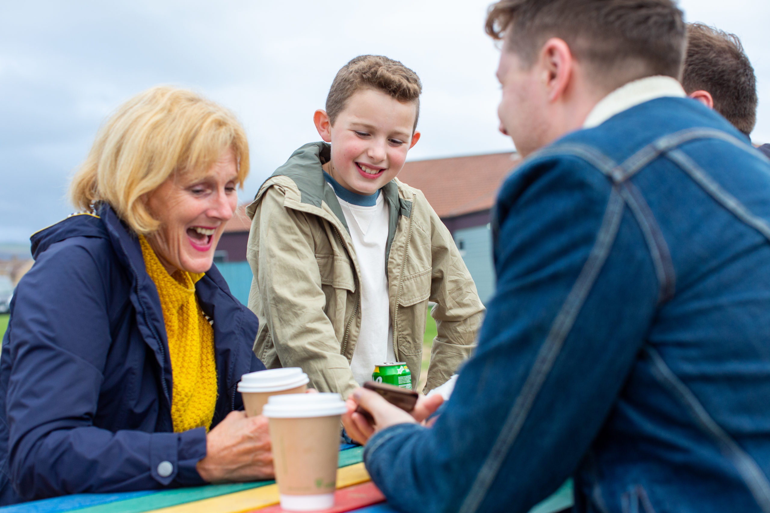 A woman, young boy and teenage boy sitting at a table laughing