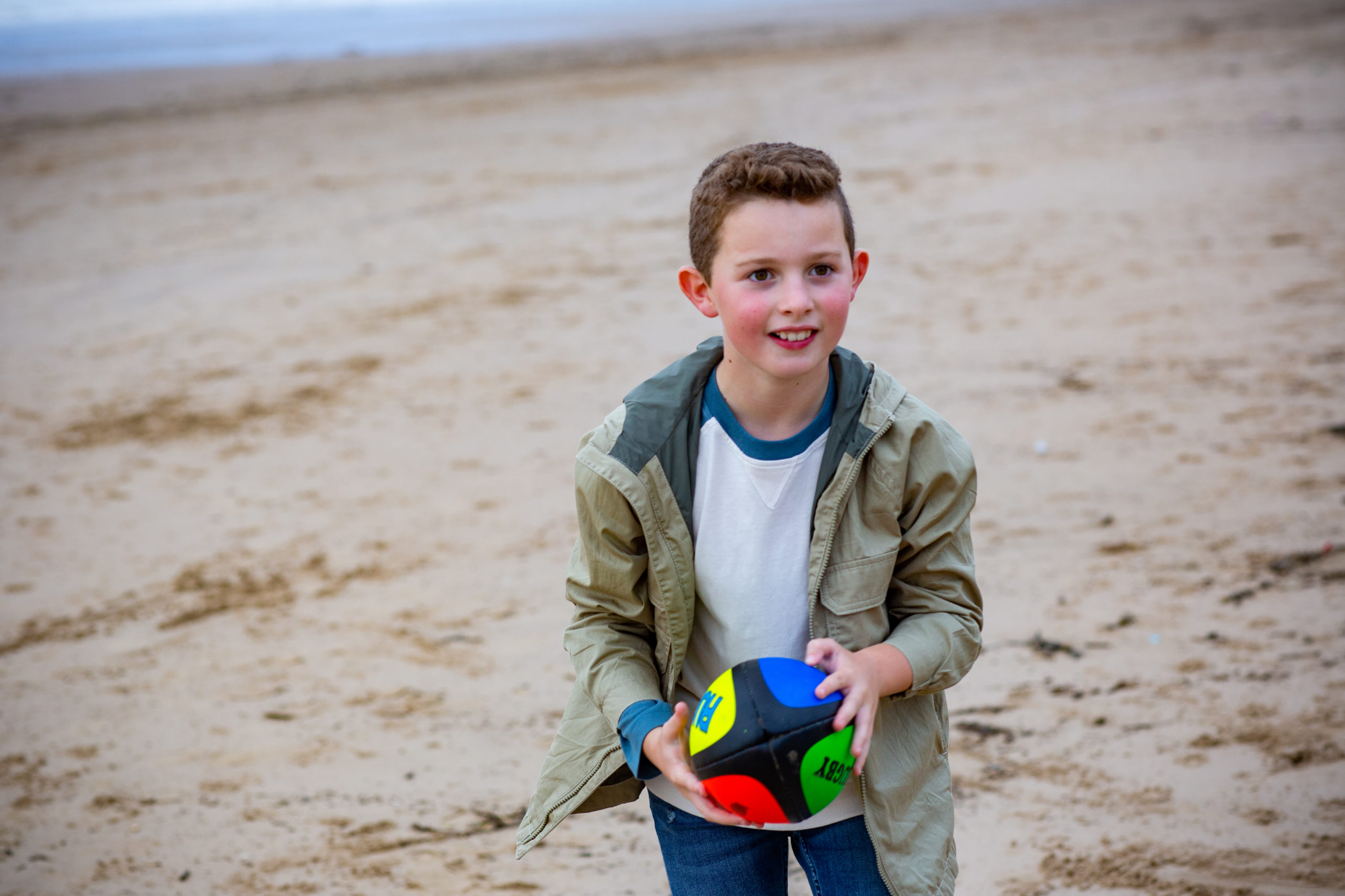 bachgen ifanc yn chwarae efo pêl