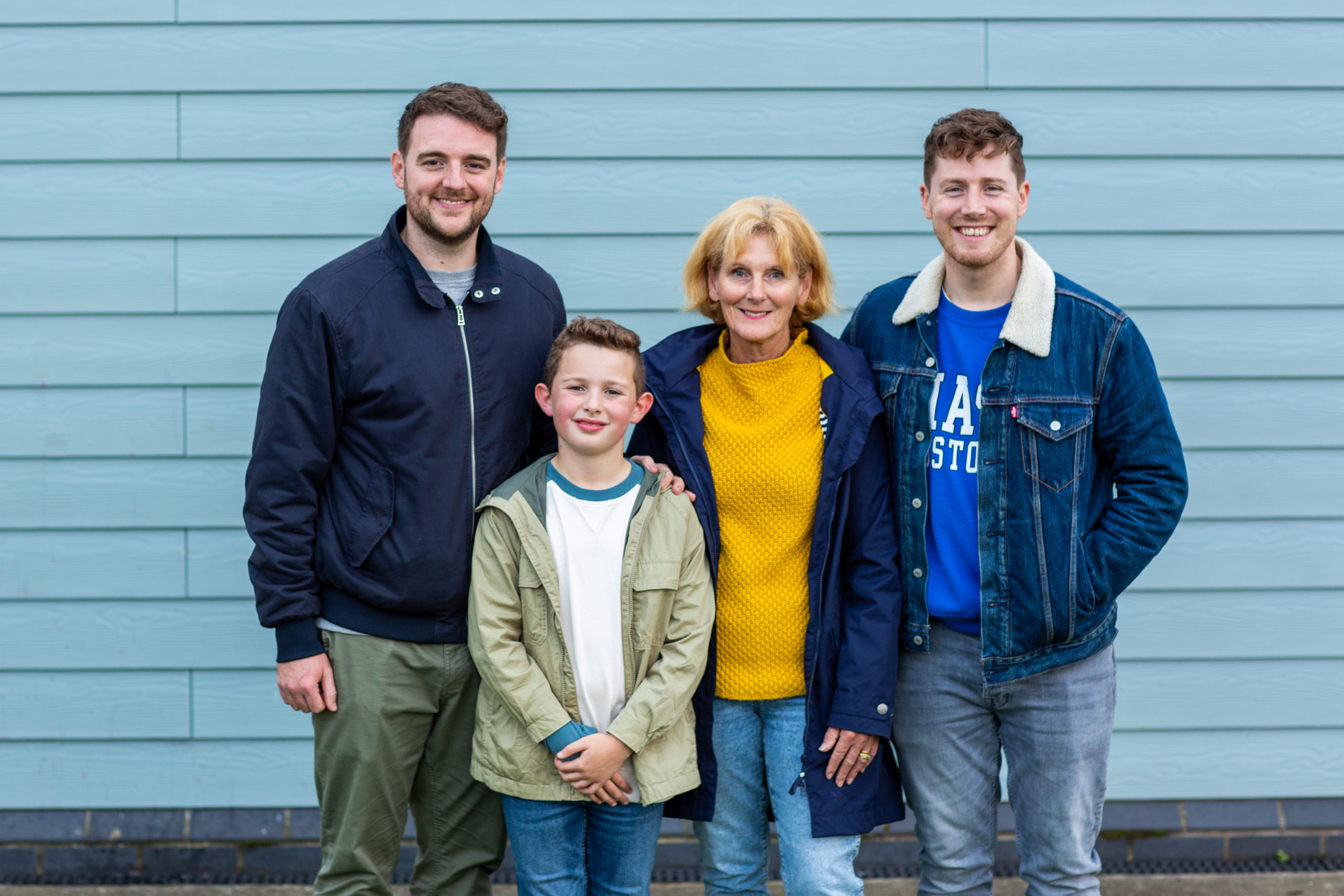 teulu yn sefyll gyda'i gilydd yn gwenu